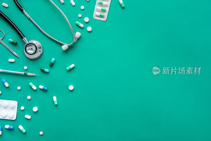药片和医疗设备在绿色背景的边界，俯视图