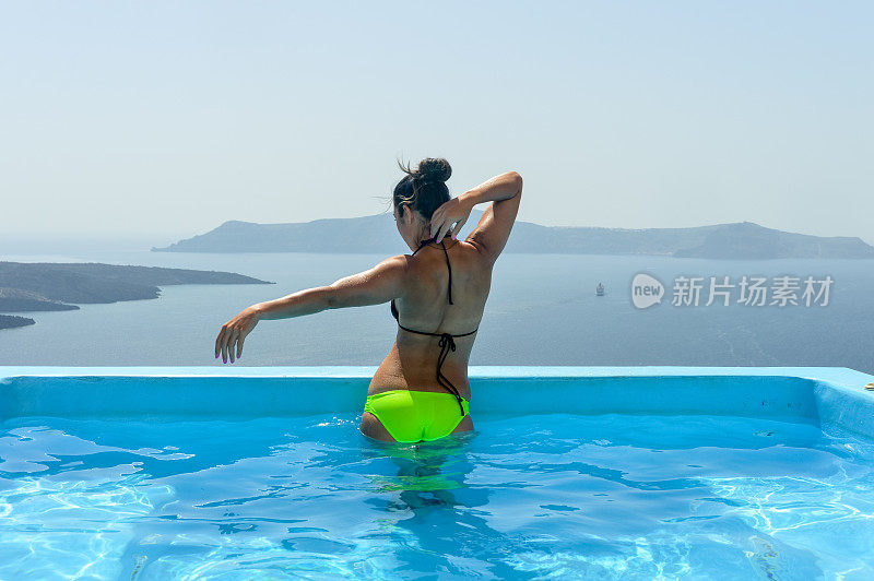 希腊圣托里尼岛一个无边泳池里的美女