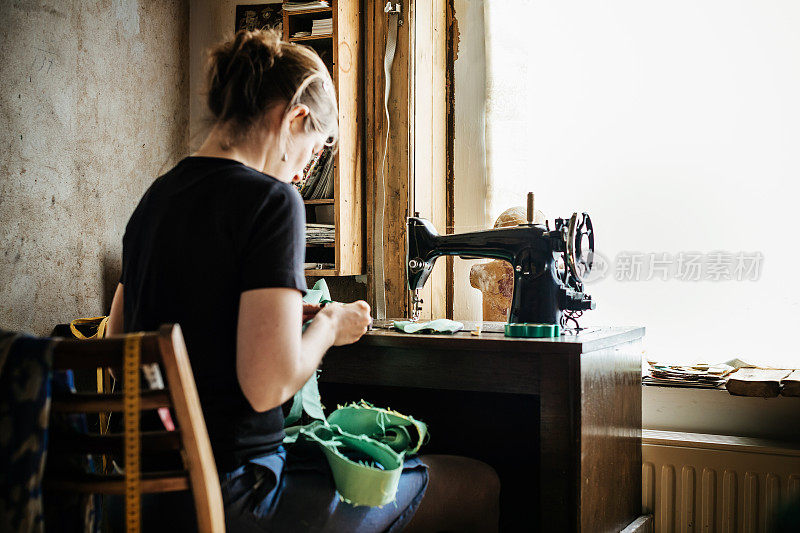 年轻时装设计师在旧缝纫机上工作