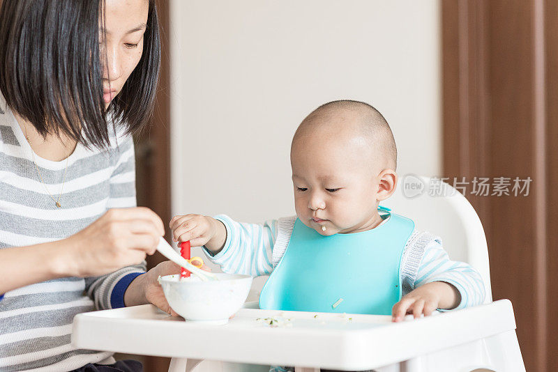 年轻的妈妈在喂她的孩子