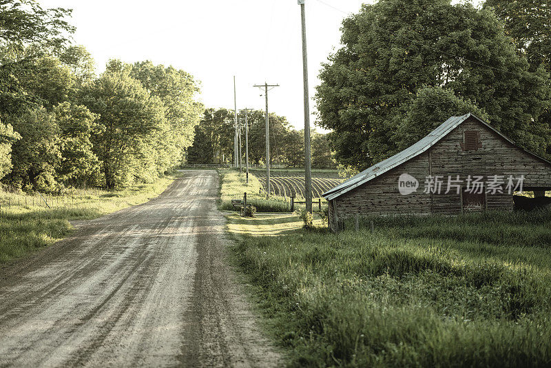 日落在一个旧谷仓和乡村道路