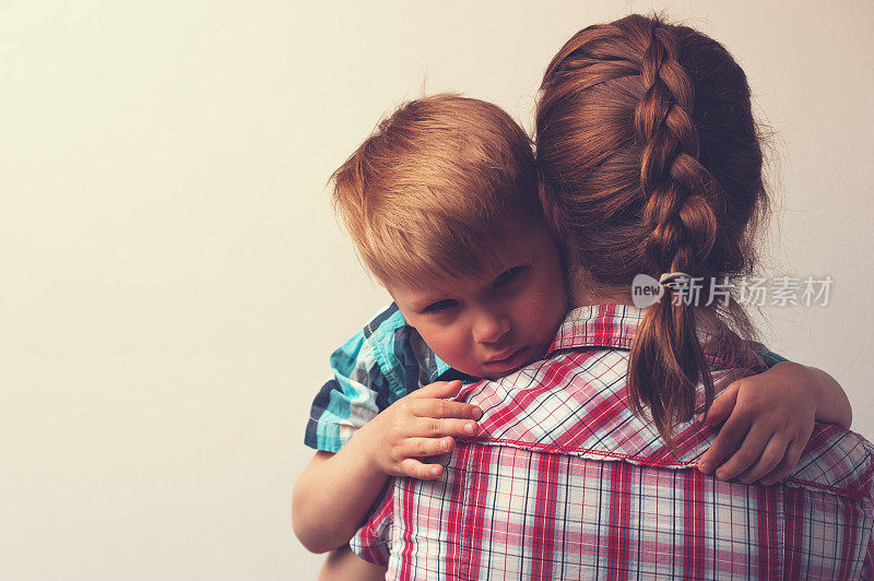 悲伤的小男孩在家里拥抱他的母亲