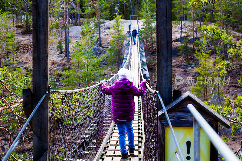 女孩在森林里的一座吊桥上行走