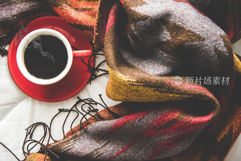 舒适的冬天家背景，一杯热咖啡与棉花糖，温暖的针织毛衣在白色的床背景，复古的色调。生活方式的概念