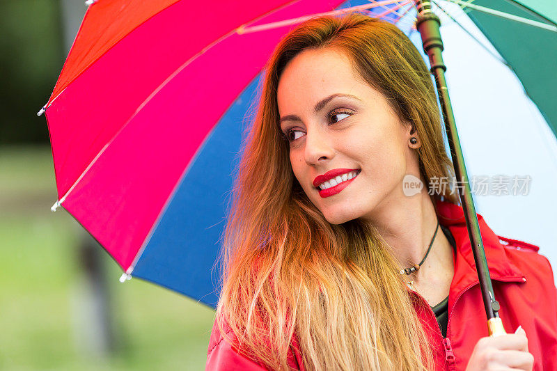 快乐的年轻女子撑着雨伞在雨中行走