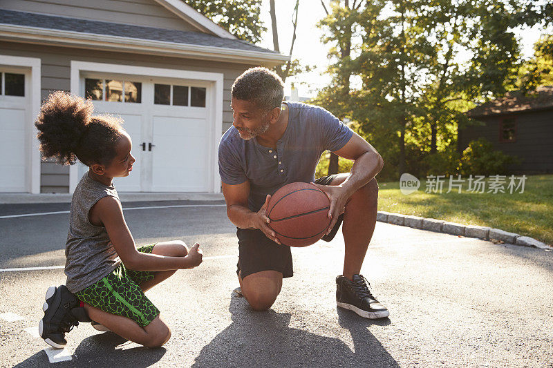 父亲在家里的车道上教儿子如何打篮球