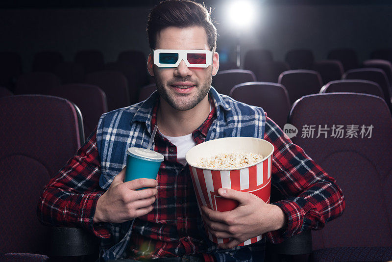 帅哥戴着3d眼镜，喝着爆米花和苏打水在电影院看电影