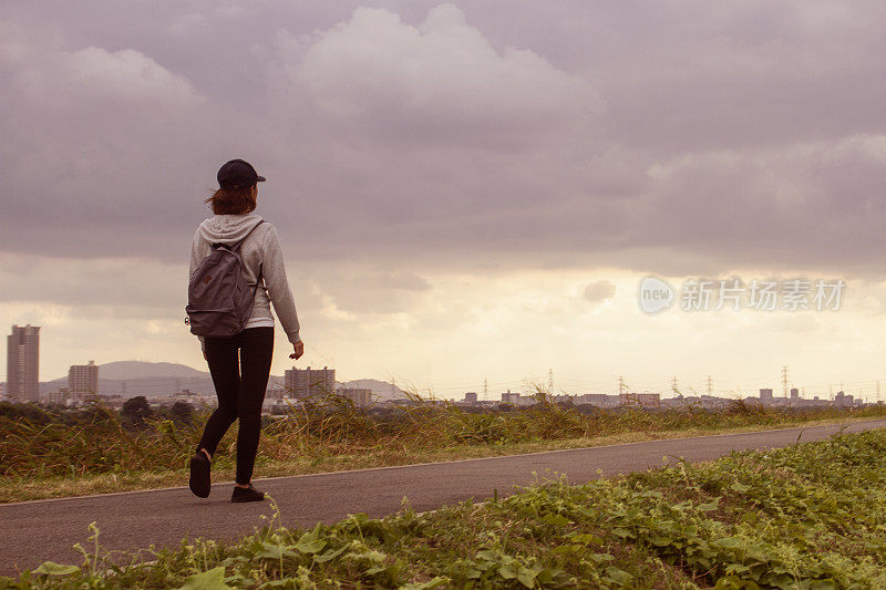 后视图的一个年轻女子走过一条小路