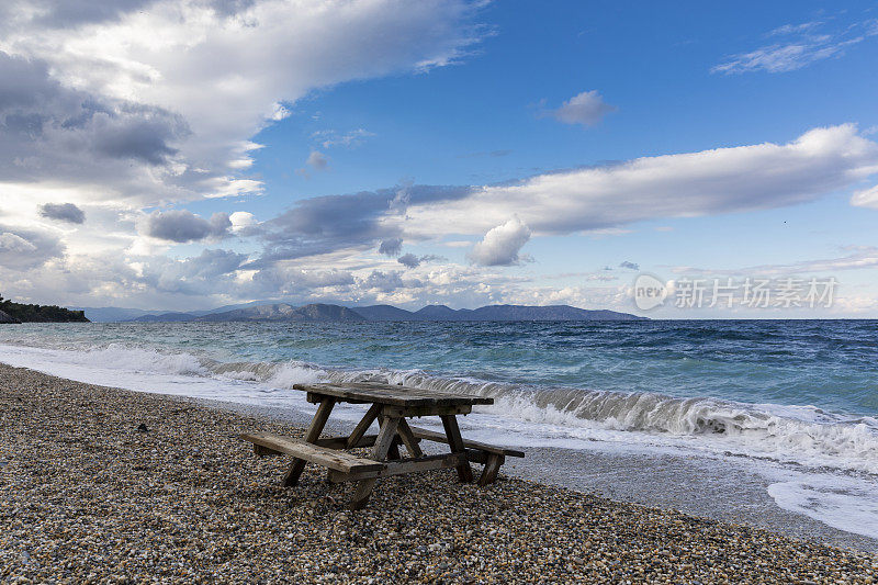 海滩上的野餐桌，波涛汹涌的大海，多风的天气