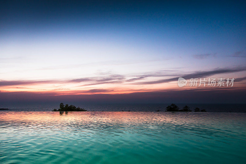 无尽的游泳池和海边的景色在黄昏