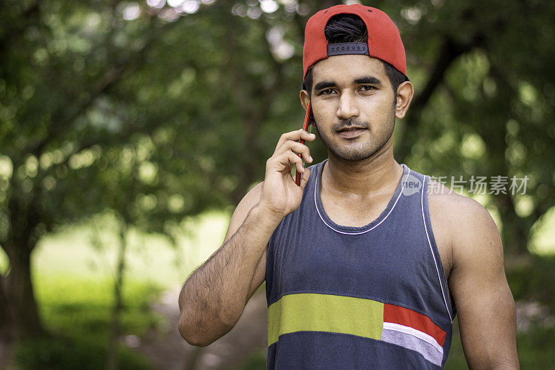 年轻的印度运动员在操场或公园慢跑后使用智能手机