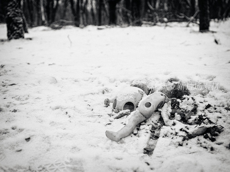 被遗弃的破损的旧娃娃在雪中腐烂