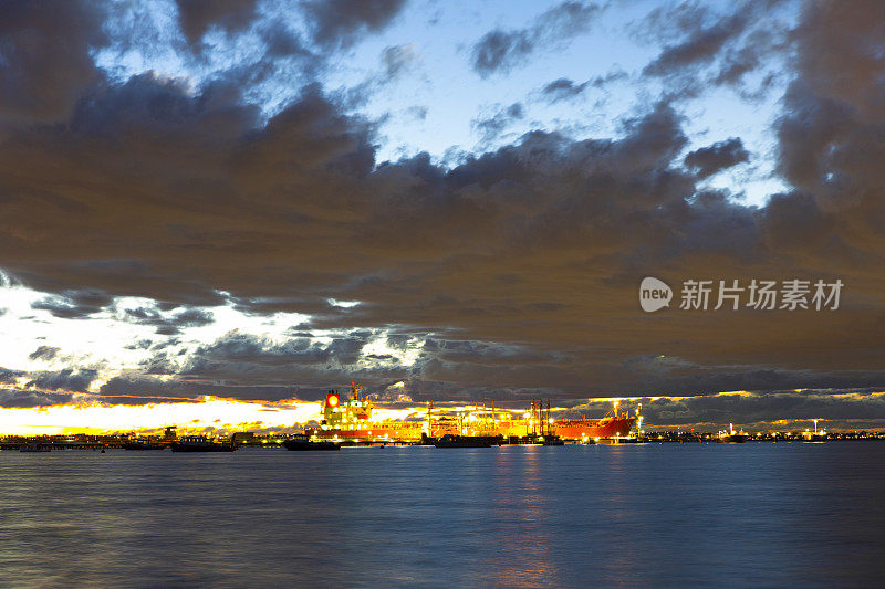 海湾在夜晚与油轮在炼油厂港口和城市天际线，背景与复制空间