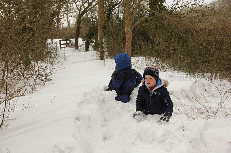 两个男孩涉水穿过厚厚的积雪