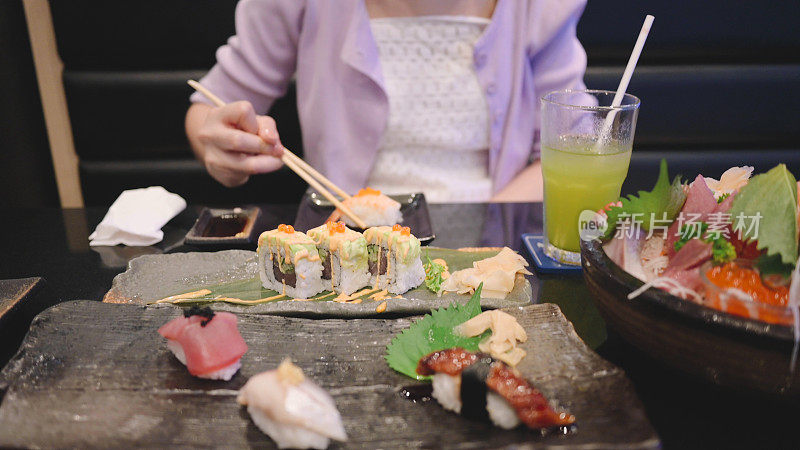 朋友们在一家日本餐厅享用豪华的日式料理，寿司、海鲜、生蚝、生鱼片新鲜出炉，摆在餐厅的餐桌上。