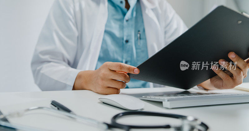 近距离的成熟亚洲男子医生使用笔记本电脑视频通话医疗结果在咨询病人在健康诊所。