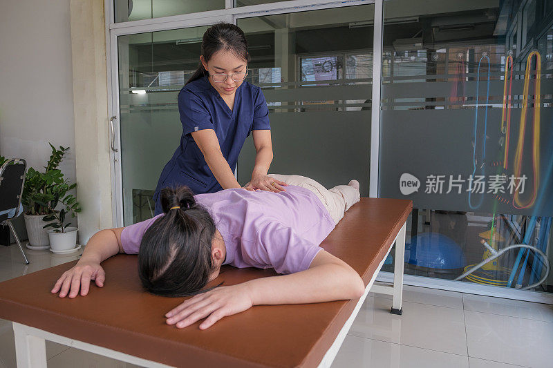 女医生或理疗师，为前来就诊的女病人进行脊椎按摩和肩部调整