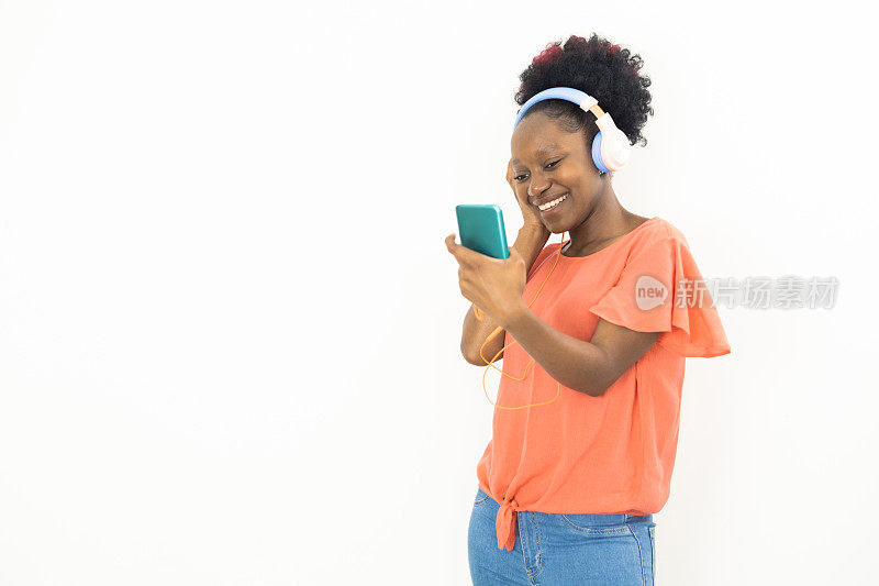 一个年轻的非洲女性的肖像在她的智能手机上播放音乐
