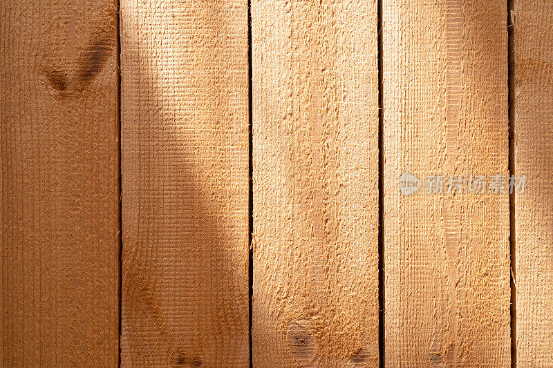 由天然颜色的未经处理的松木板制成的墙壁碎片。木头的表面很粗糙。有照明和阴影区域背景。纹理。