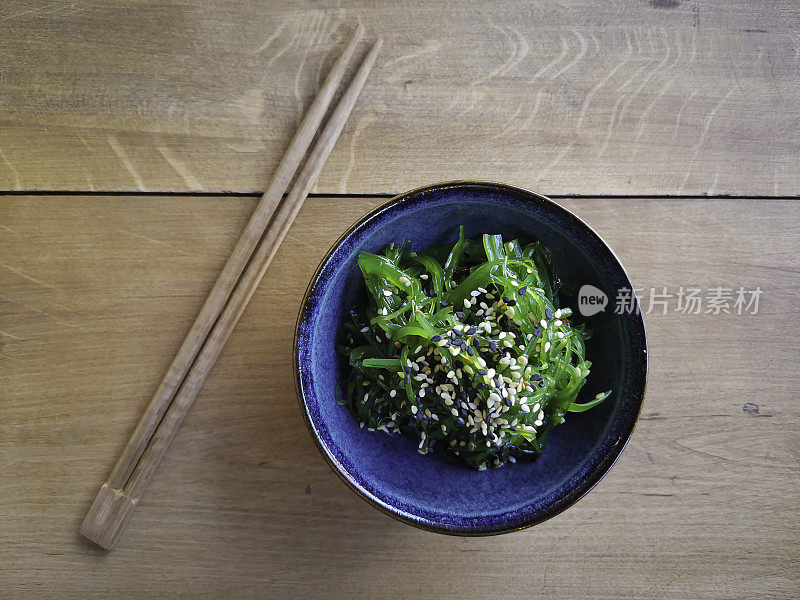 木桌上的碗里盛着日式紫菜沙拉
