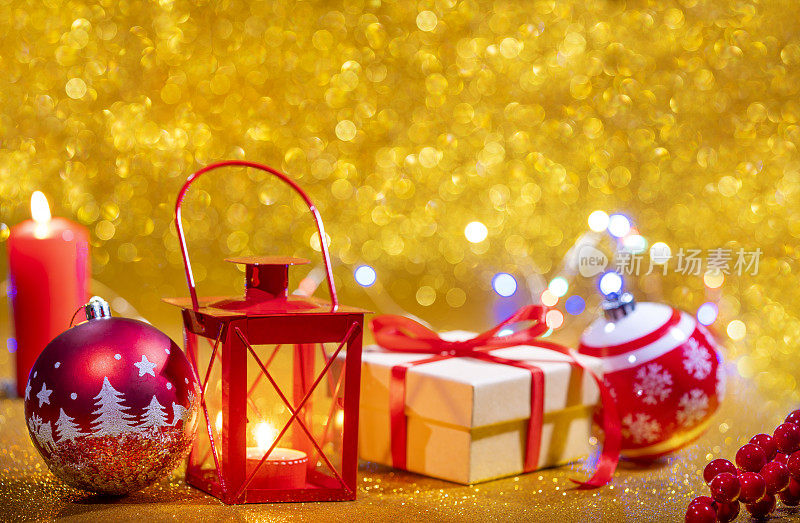 红色的蜡烛灯笼和礼品盒，金色的闪光圣诞背景和红色的小彩灯