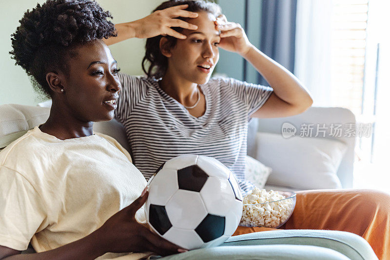 两个年轻女子观看一场激动人心的足球比赛