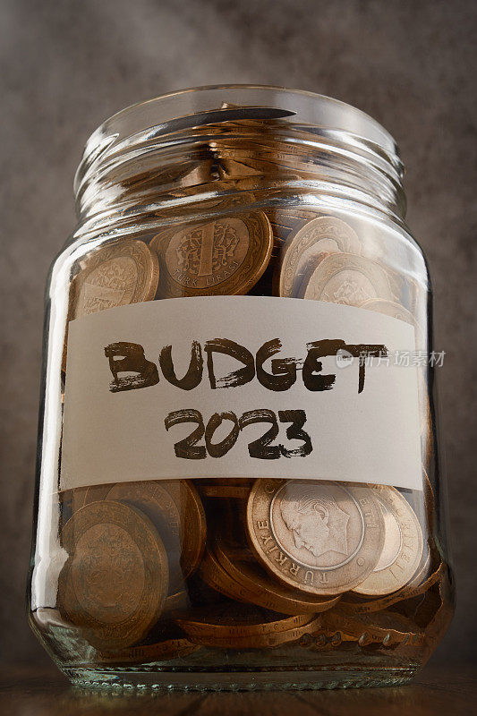 硬币储蓄罐与2023年预算文本的标签装满了硬币