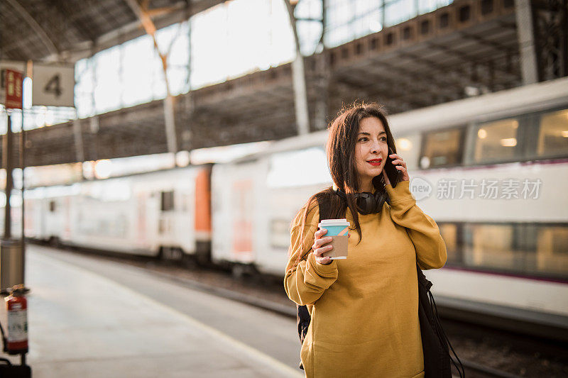 一位成熟美丽的西班牙女子在火车站等待上车时正在使用手机