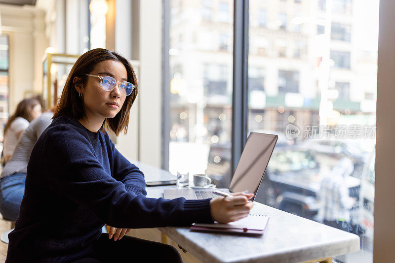 专注的亚洲学生在纽约Soho咖啡馆专心备考