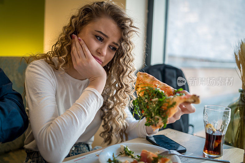 女人正从烧木头的炉子里吃披萨。在意大利餐厅吃午餐。