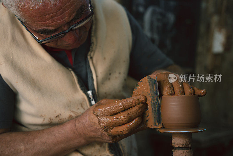 一位老人正在制作一个陶杯