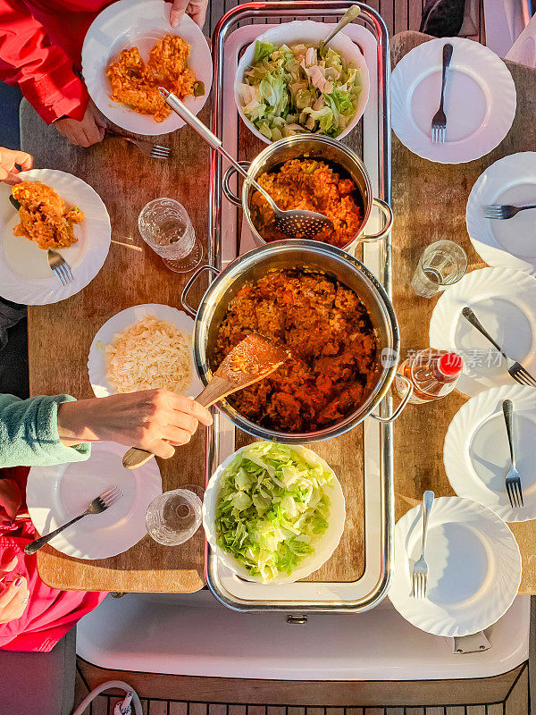 日落时分，船员们在停泊的帆船上吃晚饭