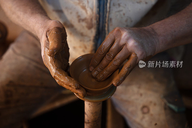 一位老人正在制作一个陶杯