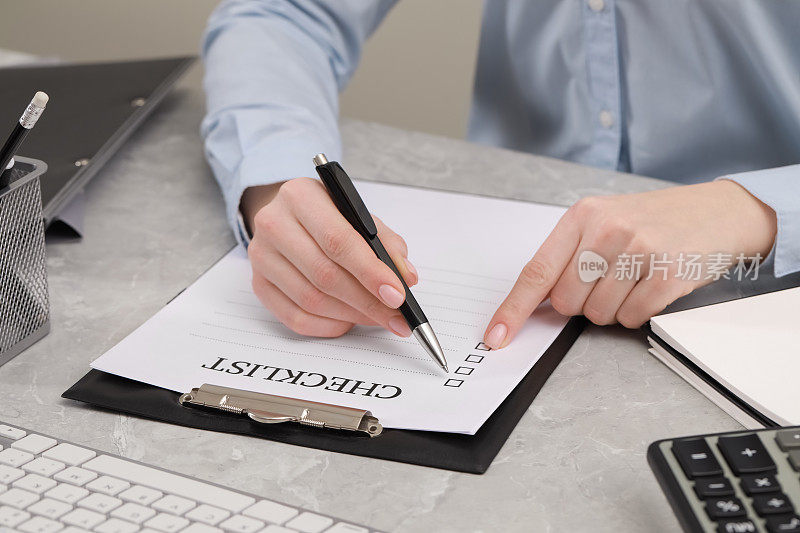 一位女士在灰色大理石桌旁填写检查清单，特写