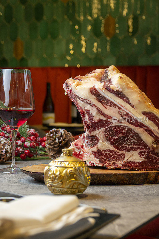 一块生肉放在桌子上，配上一杯葡萄酒和圣诞装饰品