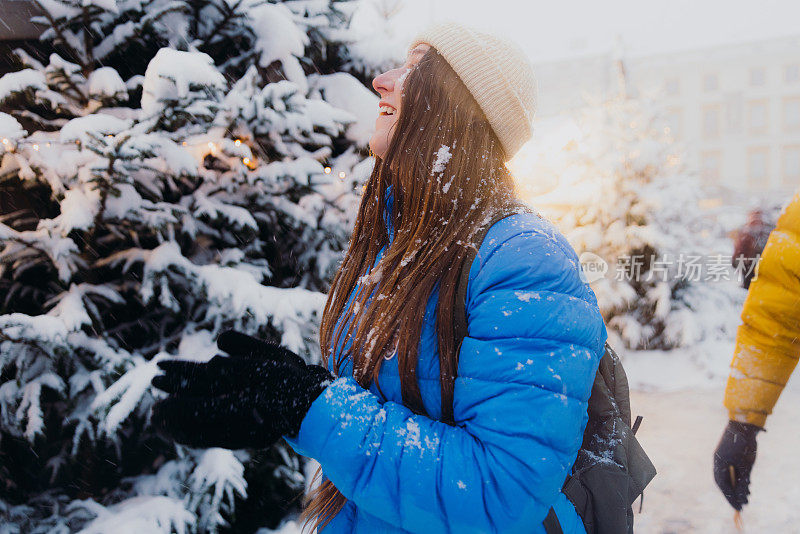 快乐的女人背着背包，在克拉科夫思考下雪的圣诞节