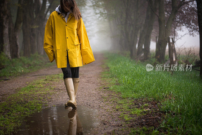 一位穿着雨衣的女性走进了水坑