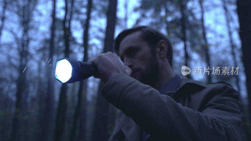 在犯罪现场，调查员手持手电筒，在多雨的森林中寻找证据