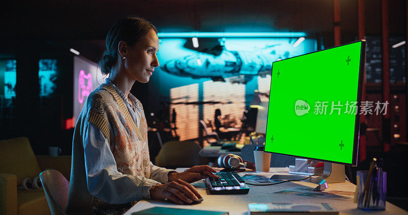 年轻女子的肖像坐在她的办公桌上使用桌面电脑与模拟绿屏。女性高加索专家工作与彩色键显示在创意机构的电脑
