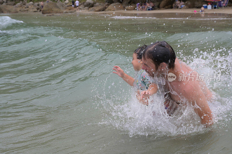 父子俩玩着海浪