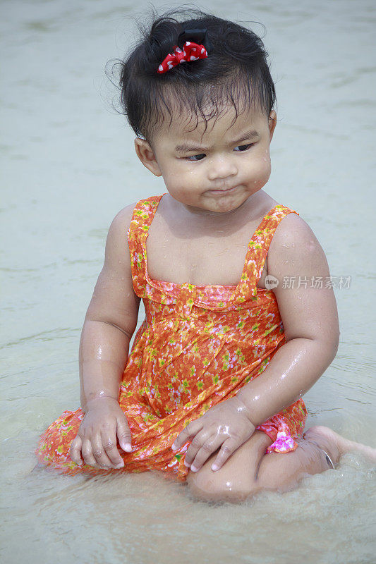 亚洲婴儿在沙滩上微笑