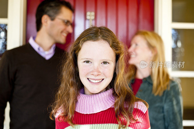 12岁的女孩在家的门廊上带着幸福的微笑