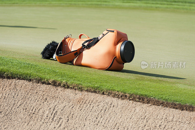 高尔夫球场果岭附近的橙色高尔夫球袋