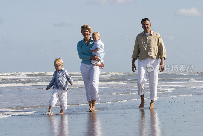 幸福的一家人沿着海滩散步