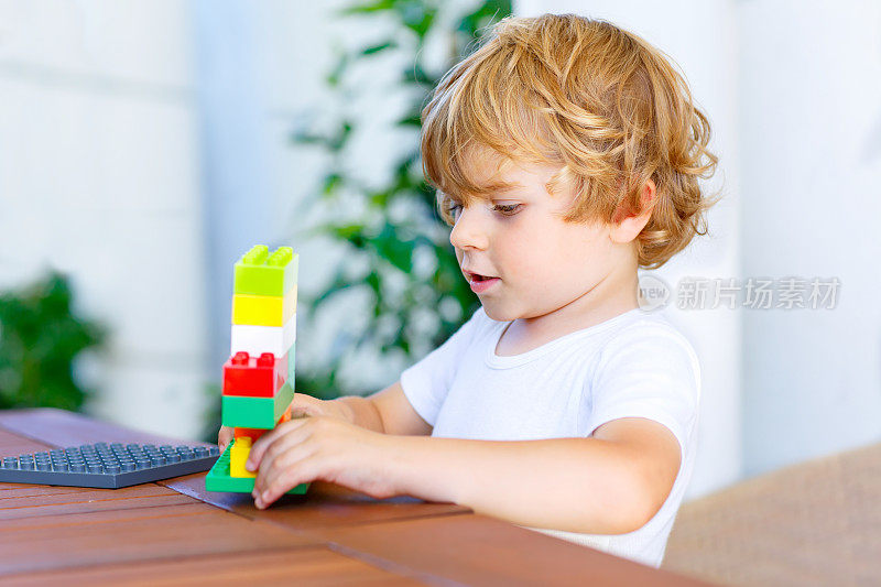 一个小男孩在玩五颜六色的塑料积木