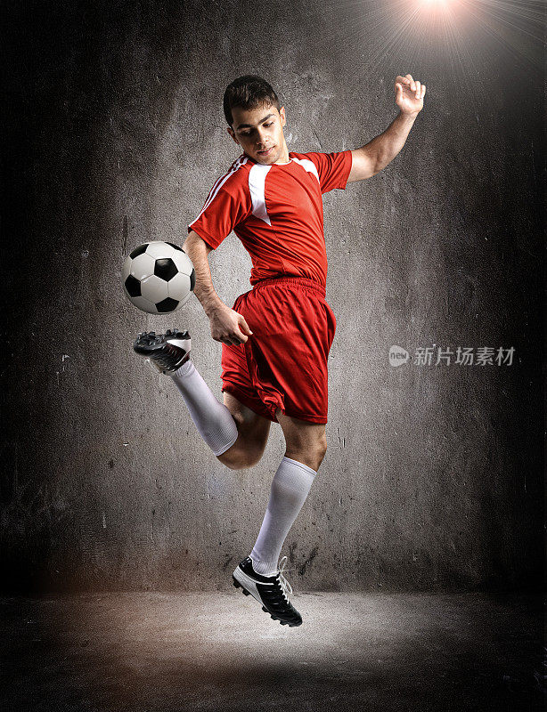 在墙壁背景上正在踢球的足球运动员。