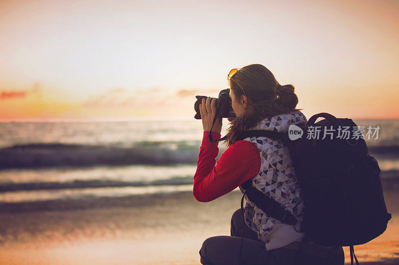 女孩摄影师在日落时分用单反相机拍照