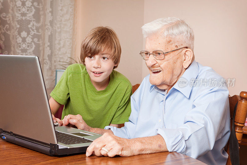 祖父和孙子一起使用笔记本电脑
