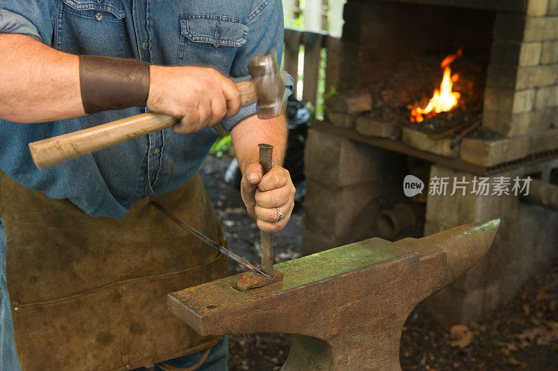 铁匠在车间里用铁砧锻造一块金属