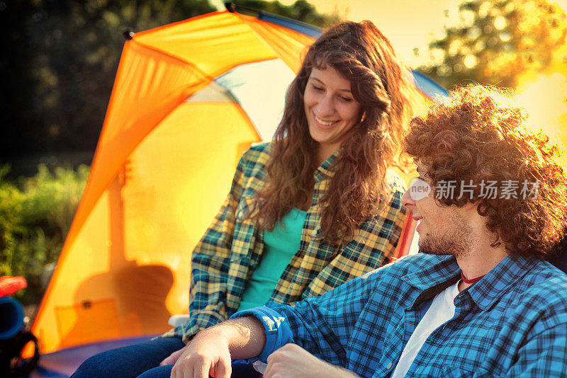 露营:日落时分，一对夫妇在帐篷附近
